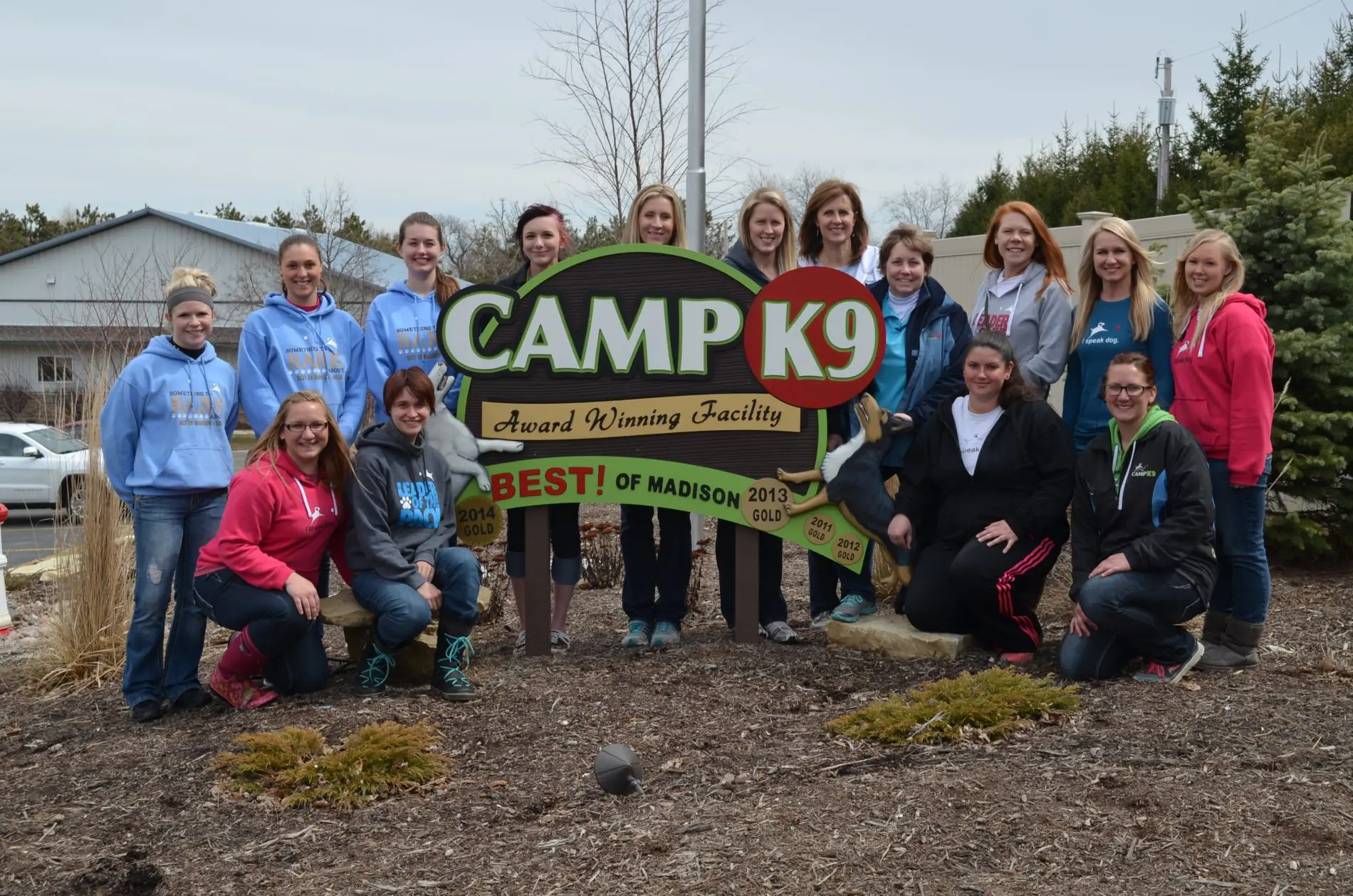 CampK9 award winning facility sign with the Camp K9 team posed around it.