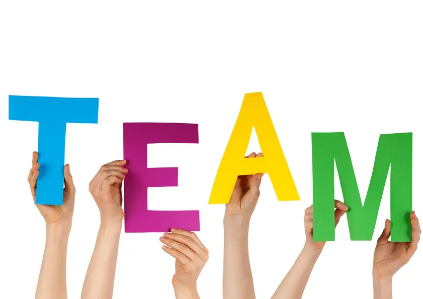 Six hands hold up blue, magenta, yellow, and green letters that spell out the word "team."