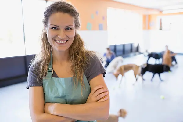 dog daycare owner wearing apron with arms crossed smiling at the camera