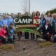 CampK9 award winning facility sign with the Camp K9 team posed around it.