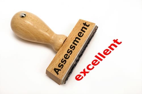 AssessmentExcellent A wooden stamp that has "Assessment" written in black on the stamp and the word "Excellent" in red next to it.